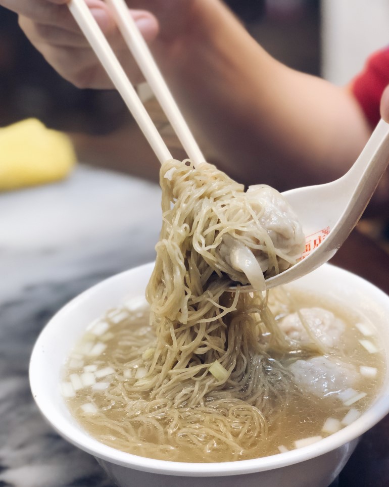 A bowl of noodle shrimp dumpling soup.